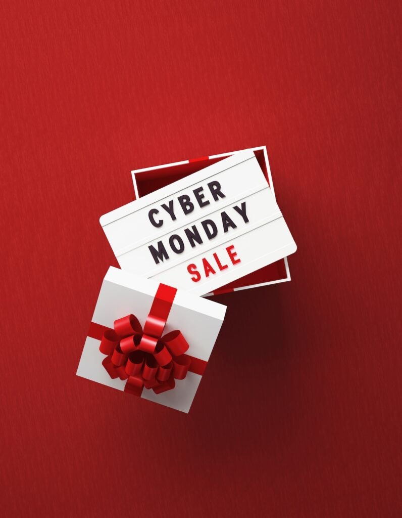 Cyber Monday Sale written lightbox sitting over white gift box on red background. Cyber Monday Sale travel tuesday