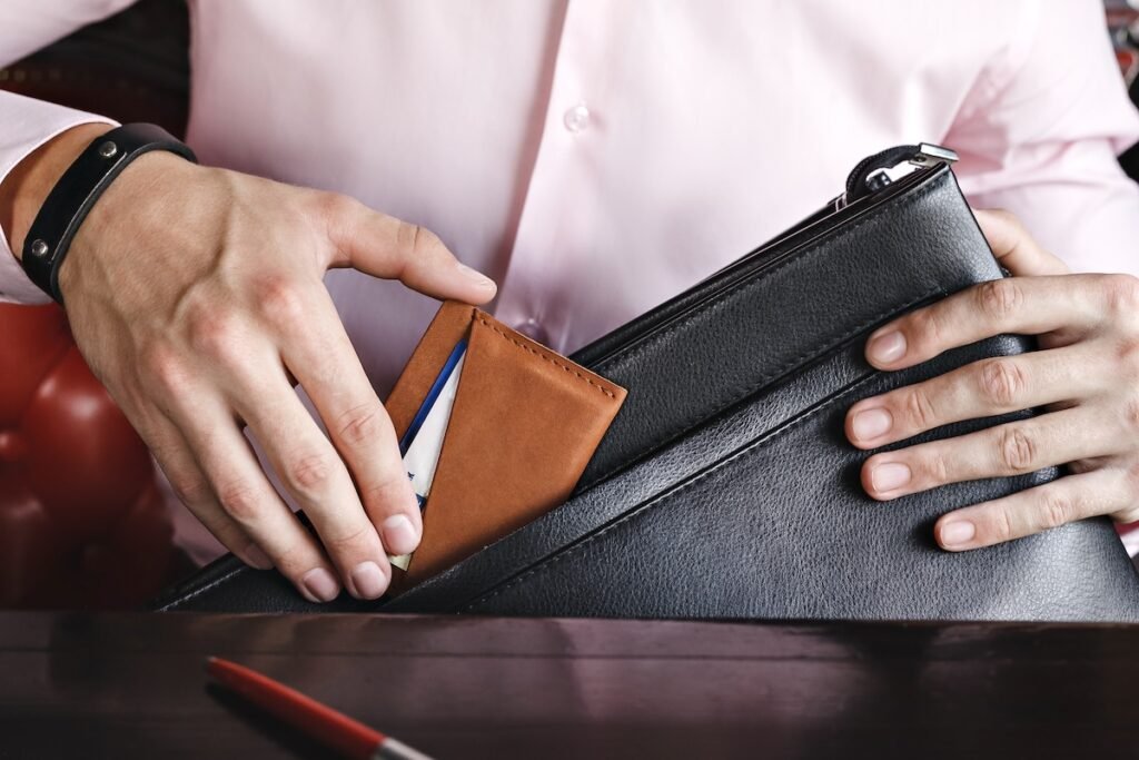 A business man puts a leather wallet with credit cards in his briefcase. RFID-blocking wallet business trips