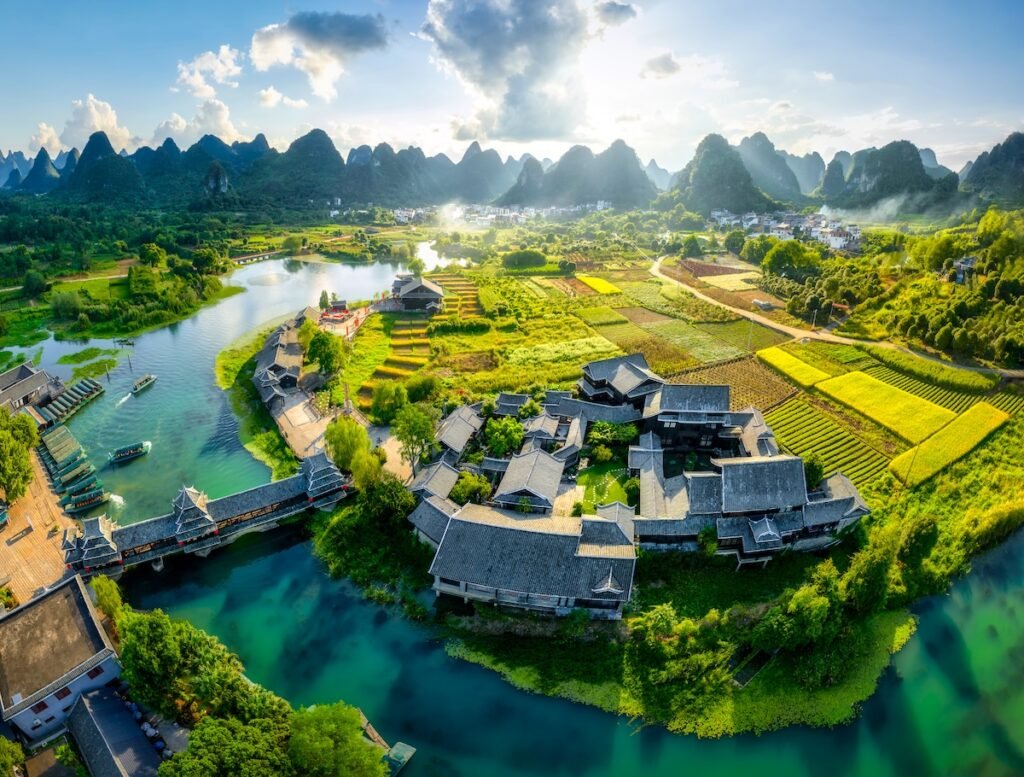 Aerial view of Shangri-la Gardens at sunset, boats in the river, rice fields and karst mountains in the background, Yangshuo, Guilin, Guangxi Province, China Asian summer