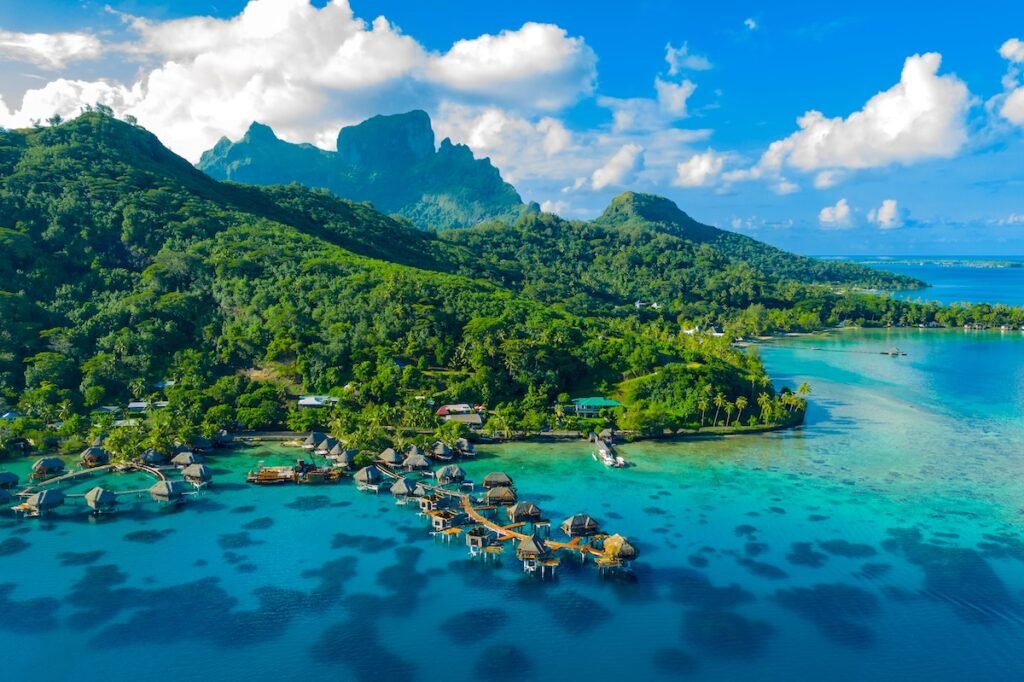 Bora Bora aerial drone video of travel vacation paradise with overwater bungalows luxury resort, coral reef lagoon ocean beach. Mount Otemanu, Bora Bora, French Polynesia, Tahiti, South Pacific Ocean