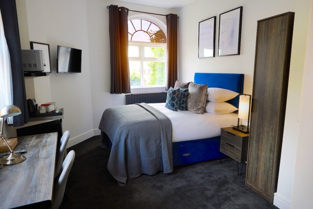 Hotel, room and interior of bed, furniture and clean area for accommodation with duvet, comforter and pillows. Empty bedroom in house, apartment or resort for holiday getaway, hospitality or home