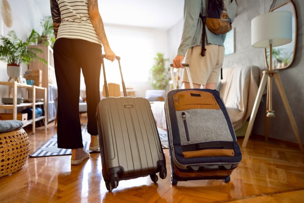 Rear-view of an unrecognizable couple arriving at the accommodation with their suitcases