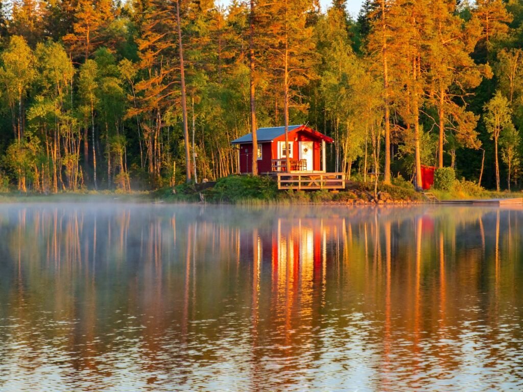 lakeside log house Sommarstuga, a Swedish summer house on the shores of foggy Lake. Idyllic Swedish landscape during summer time. Sweden. North Europe.