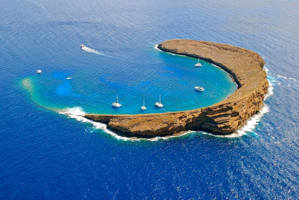An aerial view of Molokini Island Hawaii, with boats moored inside