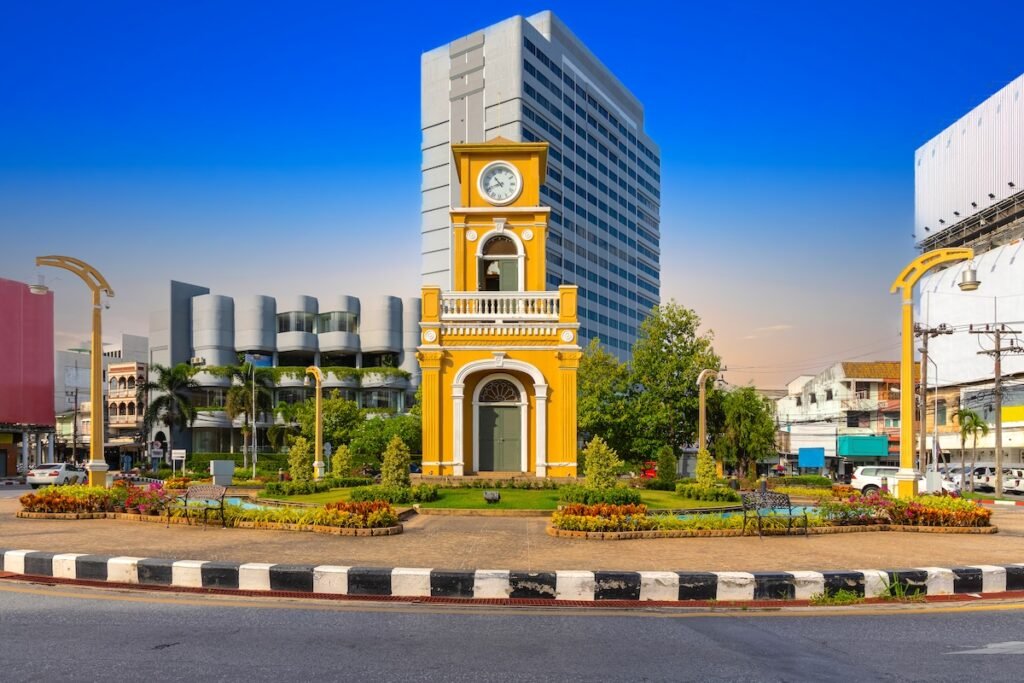 Clock tower on a roundabout in old phuket town at during the summer day surrounded by high-rise buildings and Hotels in phuket thailand.