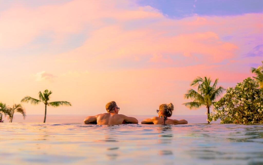 Romantic couple looking at beautiful sunset in luxury infinity pool