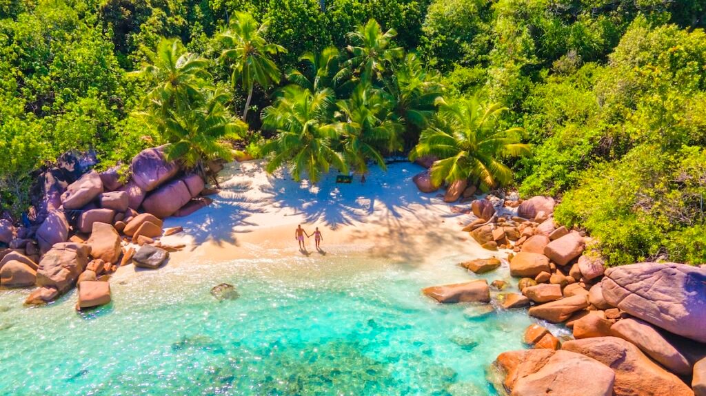 Praslin Seychelles tropical island with withe beaches and palm trees, couple of men and women mid age on vacation at Seychelles visiting the tropical beach Anse Lazio Praslin Seychelles. drone view