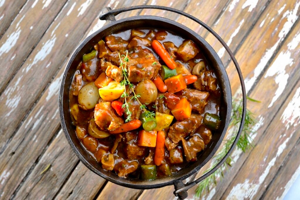 Traditional South African pot stew or potjiekos in the three-legged pot used to cook this dish on an open fire. Usually served with rice dished with a large spoon. Your Ultimate Guide To The Best African Summer Travel Spots