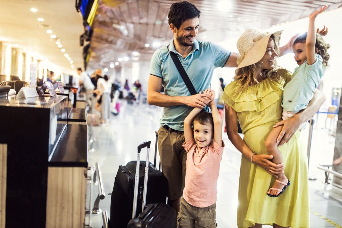 Happy family with kids at airport check-in ready for their trip &mdash; how to use TripIt for family travel