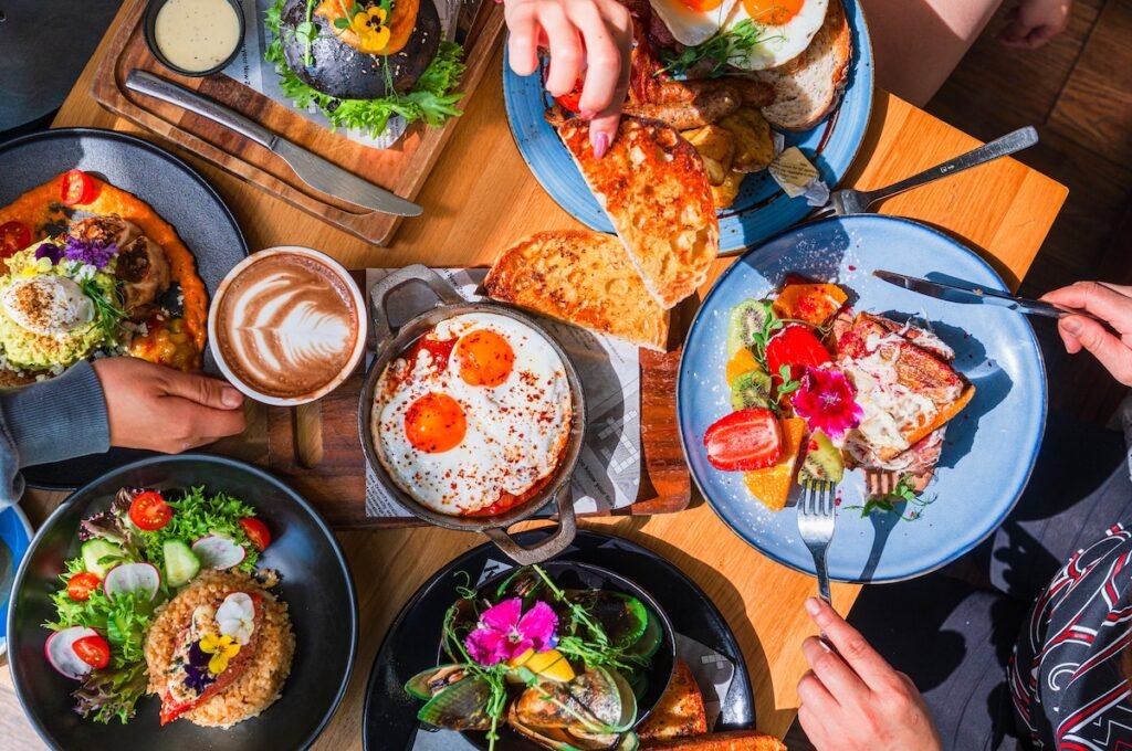 Table top view of breakfast food displayed on table, people eating food. summer vacation