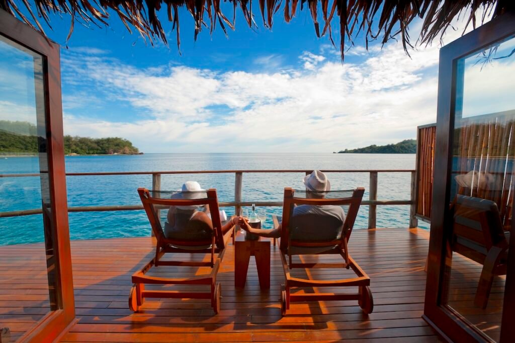 Couple relaxing on sun lounges in an over water bungalow