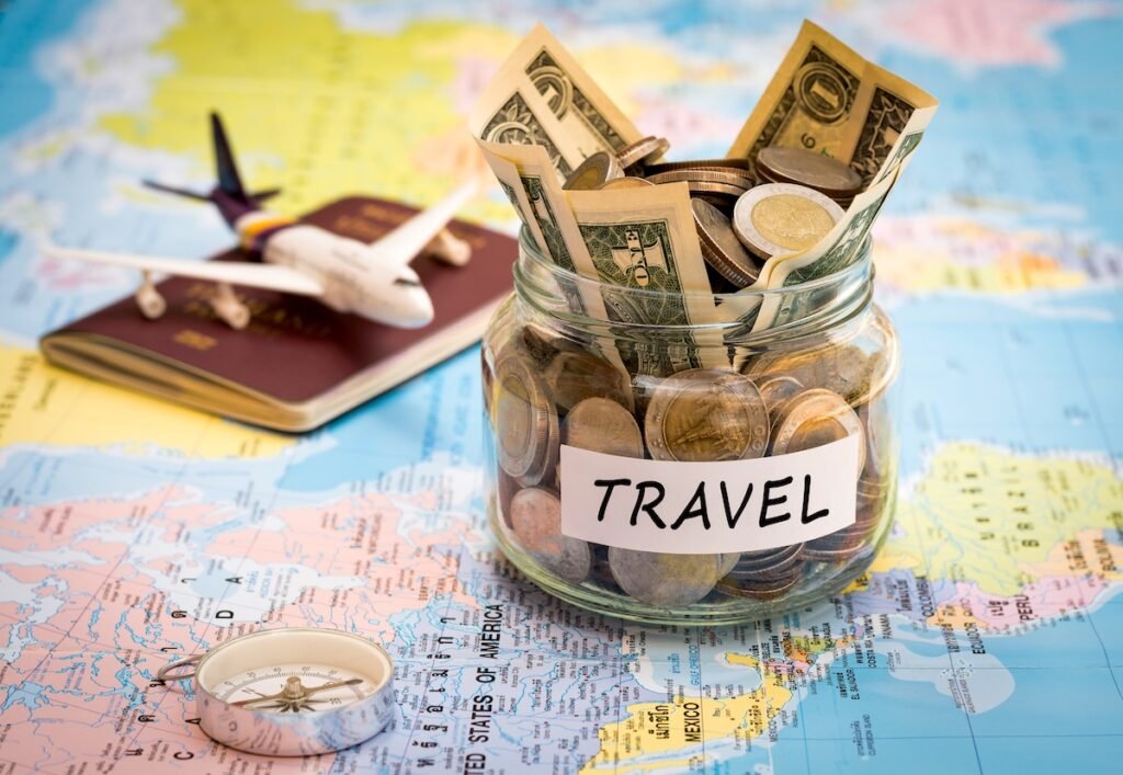Travel budget concept. Travel money savings in a glass jar with compass, passport and aircraft toy on world map