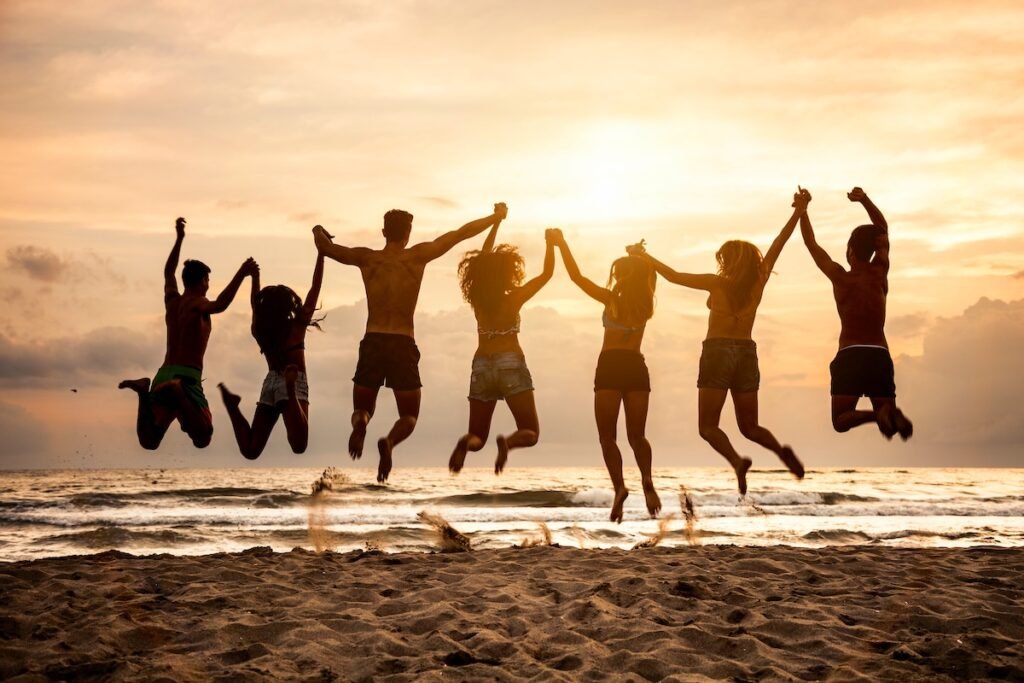 Group of friends jumping on the beach all together, happiness and relax on vacation.