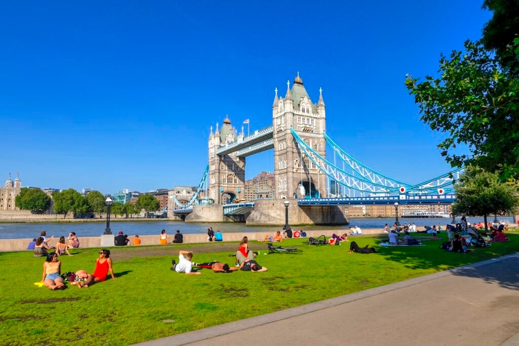 London, United Kingdom - 07 Sep 2021. Londoners and tourists enjoying the summer sunshine sitting on the grass with Tower Bridge stretching across the River Thames in the background against a clear blue sky. Eurostar Destinations That Make the Ultimate Romantic Getaway in 2025