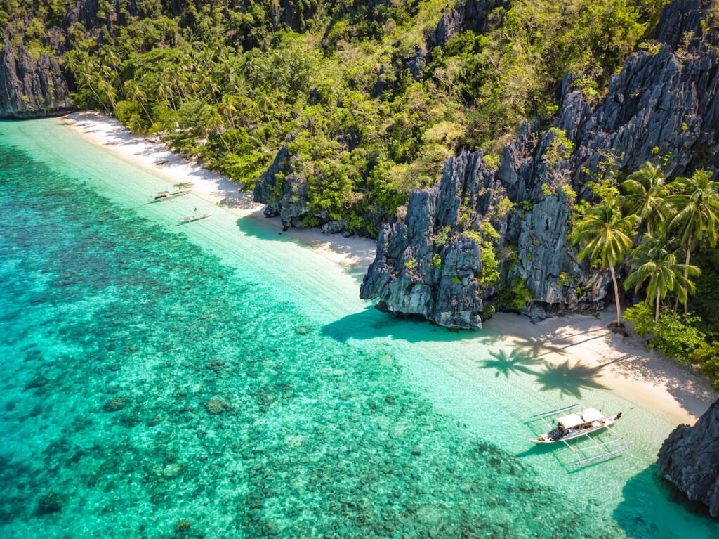 El Nido Entalula Island Beach Lagoon Aerial Drone Point of View with filipino Bangka Tourboats anchored at the pristine sandy beach. Entalula Beach, Bacuit Bay, Mimaropa, El Nido, Entalula Beach, Palawan, Philippines, Southeast Asia, Asia