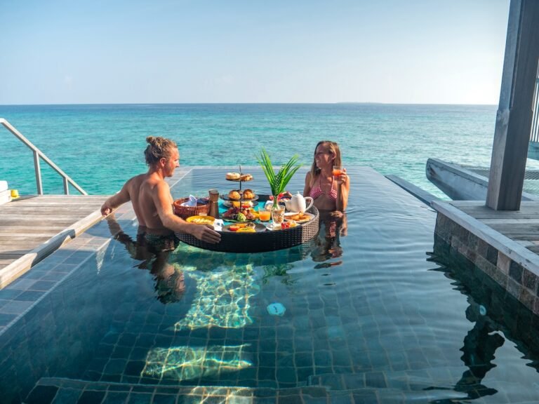 Couple enjoying tropical vacations from an infinity pool in private over water villa. People travel luxury holidays