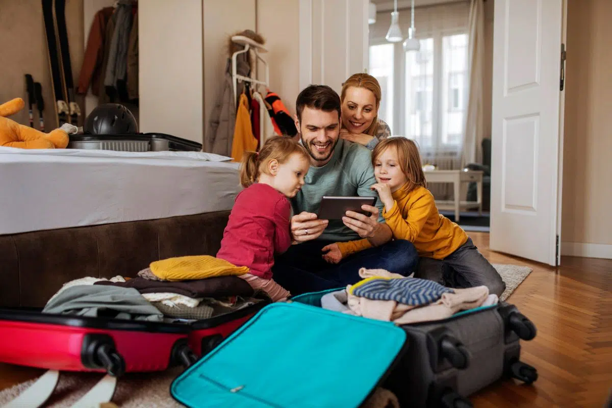 Family sitting with suitcases comparing Expedia vs Travelocity for family vacation package deals