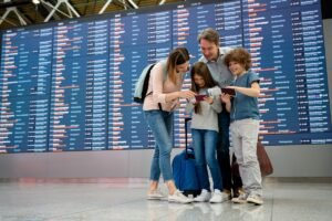Family checking flight tickets at airport departure board before cheap family flight to Europe