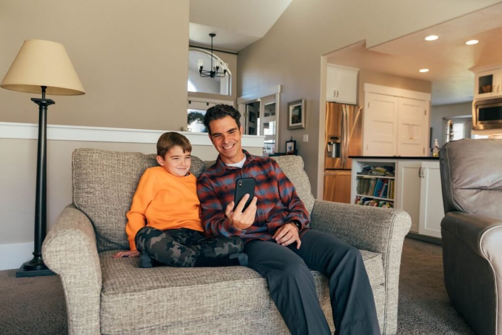 dad son sofa phone home budget travel apps families budget travel apps for families