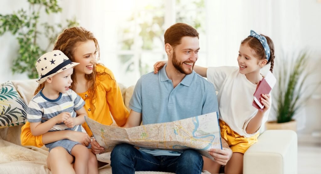 Family of four on sofa looking at travel map together and smiling — how to plan a family trip itinerary. how to plan the perfect family trip itinerary