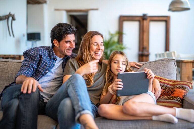 Parent using a free budget travel app on phone at home with kids &mdash; budget travel apps for families