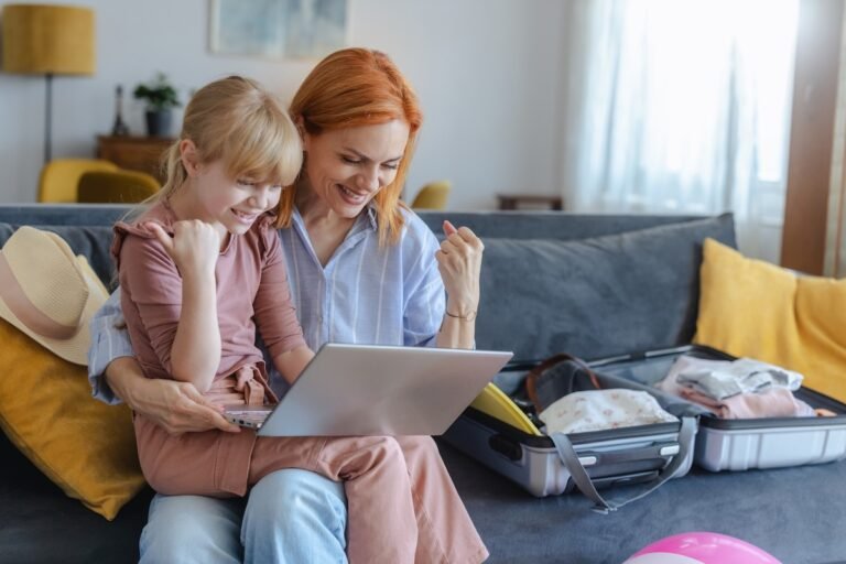 Mom and daughter celebrating finding a cheap flight deal on laptop at home — Travel Tuesday flight deals for families